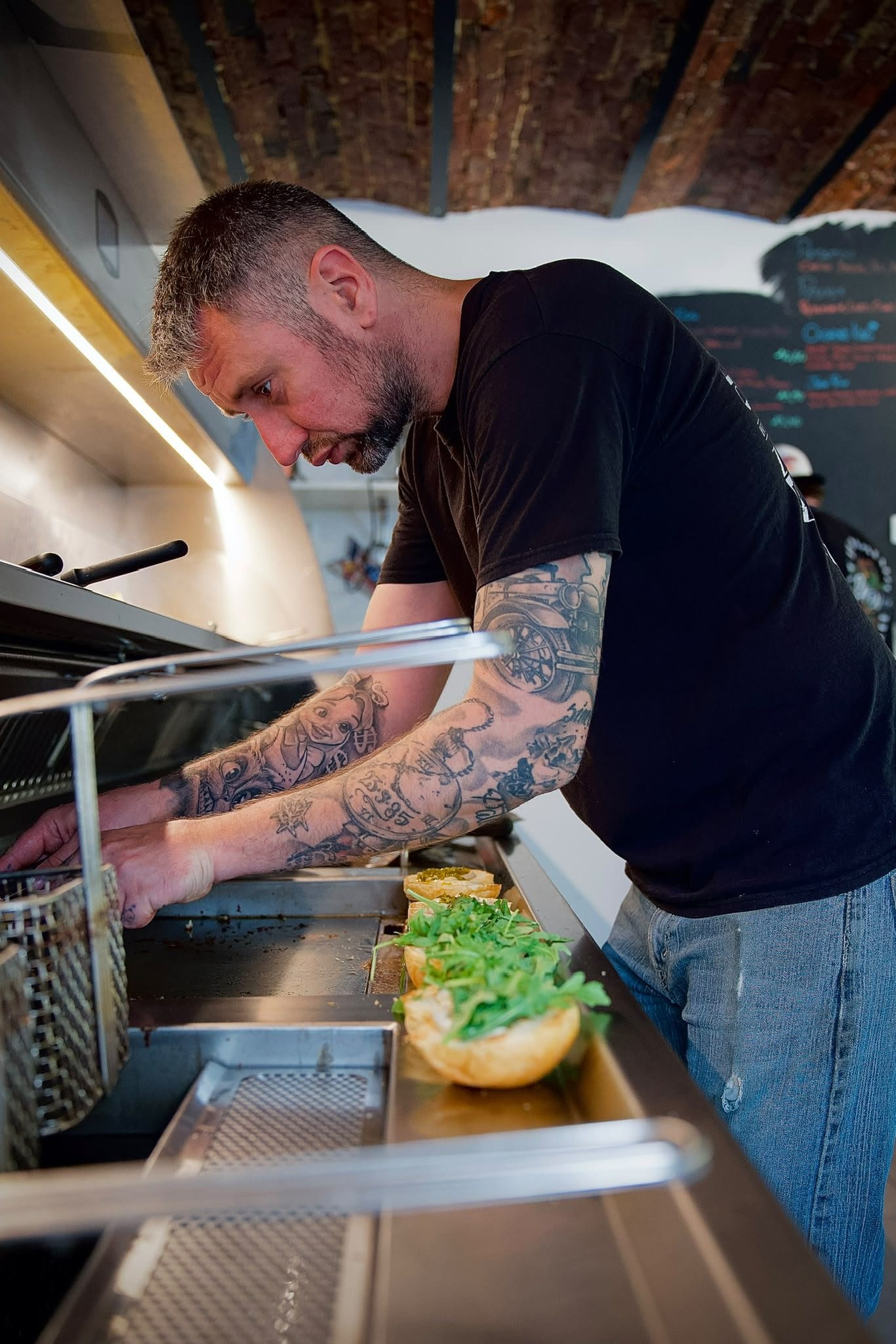 Un des deux patrons aux friteuses, en train de dresser un burger.